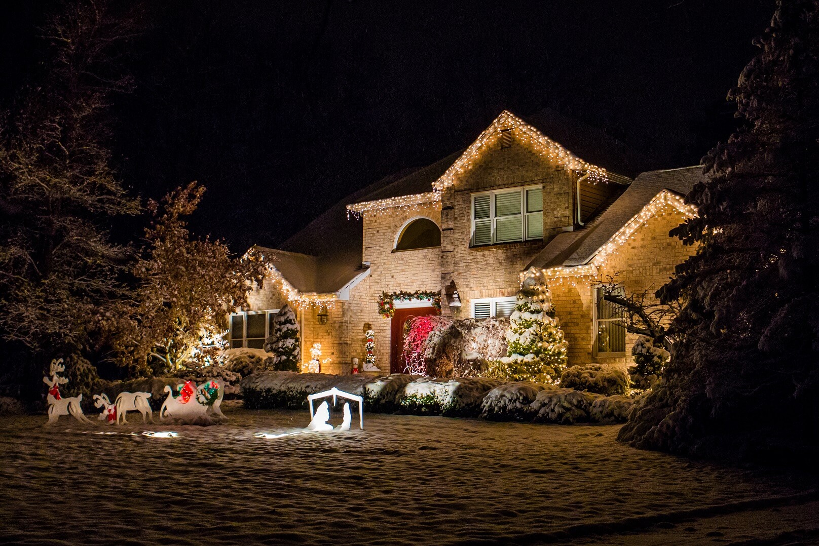Two-story home with warm white roofline lights and a decorated front yard